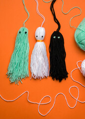 diy halloween ghosts from threads on orange background. vertical photo
