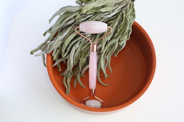 Pink face roller laying on white background. Beauty tools. Quartz derma roller for skin treatment. 	