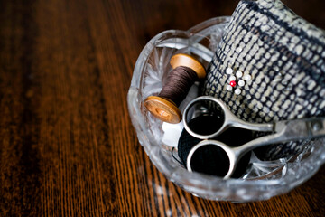 Tools for darning clothes. Scissors, spool of thread and pins in a crystal vase. Place for text