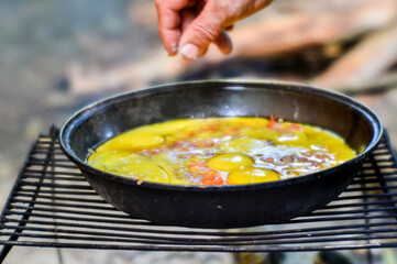 Fried eggs are cooked in a pan over an open fire in a country house. Sharpness in the haze in the center of the dish.