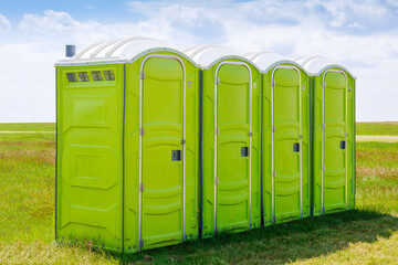 Portable toilet on the grass on a background of clouds.