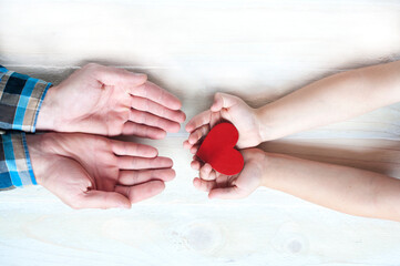 The child holds out his hands to his father. Heart in the hands of a child. Parenting concept.