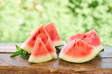 Pieces of ripe red watermelon are on a wooden plank, outdoor