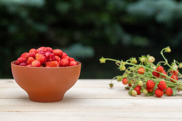 A clay cup with red, juicy strawberries stands on a wooden table