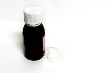 A medicine bottle with empty measurement cup in a white background with spaces for text