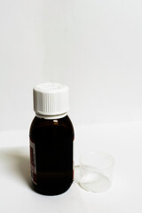 A medicine bottle with empty measurement cup in a white background with spaces for text