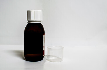 A medicine bottle with empty measurement cup in a white background with spaces for text