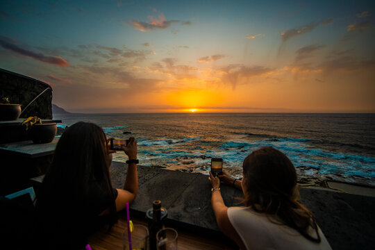 Two women having pictures at beach sunset.