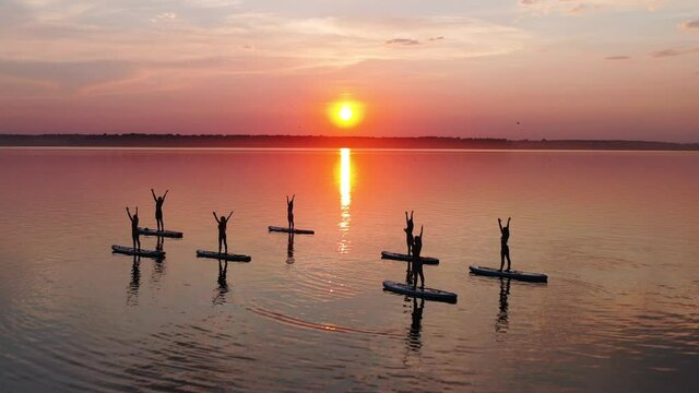 Group of people on the sup boards do yoga