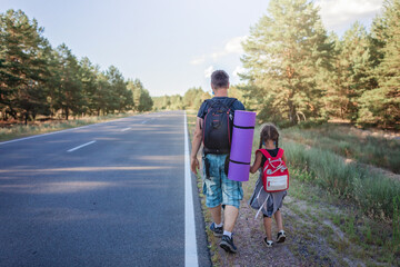 Local traveler. Father with girl with backpacks in medical masks stopping car on the road