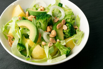 Green Salad with Avocado, Cucumber and Nuts on White Plate