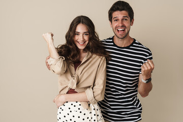 Fototapeta premium Image of excited beautiful couple making winner gesture and screaming