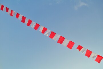 Indonesian flag waving in the wind against a blue sky and clouds. Red and white flag. Independence of Indonesia