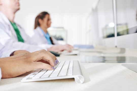 Close-up image of female doctor working on computer in medical office and entering patients data in online form