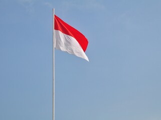 Indonesian flag waving in the wind against a blue sky and clouds. Red and white flag. Independence of Indonesia