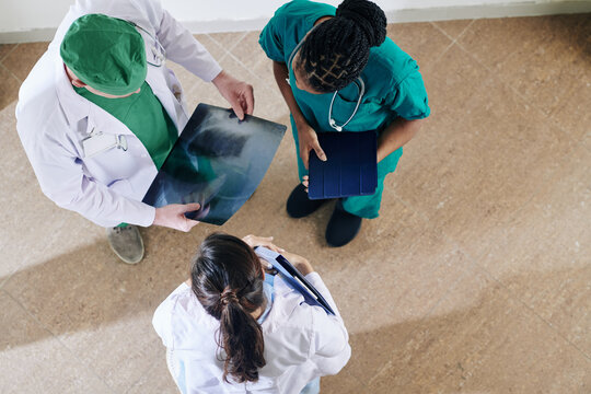 Doctor Showing Chest X-ray Of Patient To Colleagues And Asking For Their Opinion, View From Above