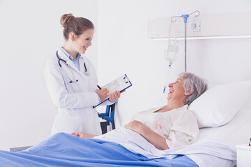 Doctor or nurse chatting to a senior woman patient - 366060016