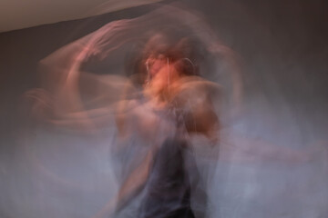 A long exposure shot of an unrecognizable young Caucasian woman dancing in her room
