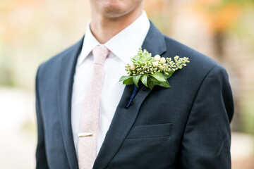 simple boutonniere on lapel of groom's suit or tuxedo with pink tie