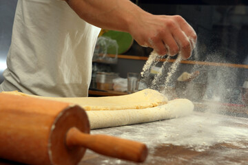 Confectioner sprinkles the flour while kneading the dough