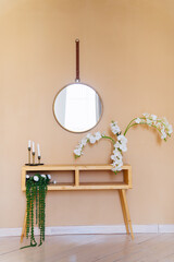 table with flowers, round mirror hanging on wall
