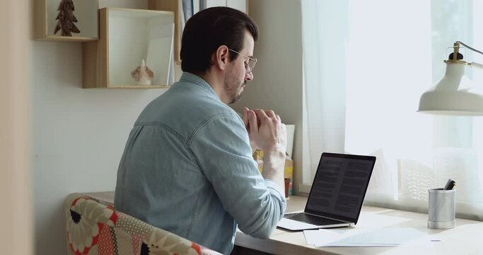 Side view man sit on chair at desk use laptop makes research, report, essay corrections, check linguistic grammatical components of text. Writer create chapter, work on diploma or dissertation concept