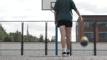 Portrait of serious attractive woman basketball player playing basketball alone on local court