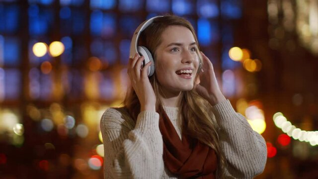 Smiling girl listening music headphones outdoor. Happy woman having fun outside