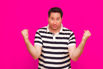 Joyful man in striped t-shirt gesturing index finger hand on camera isolated over magenta background
