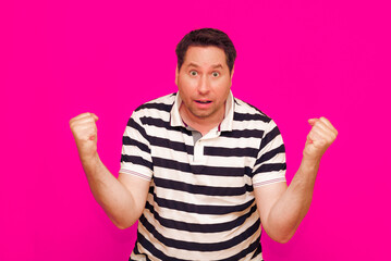 Joyful man in striped t-shirt gesturing index finger hand on camera isolated over magenta background