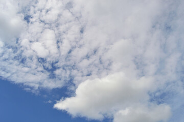 Summer background with blue sky and fluffy white clouds in daylight.