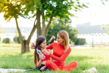 Cute smal daughter and mother do exerciese, fitness, yoga in morning park