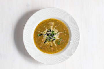 bowl of vegetable cream soup with sour cream and herbs on white wooden table