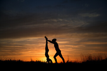 mom and daughter doing yoga outdoors at sunset