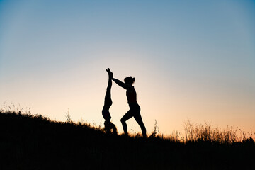 mom and daughter doing yoga outdoors at sunset