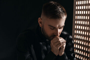Young priest in confession booth