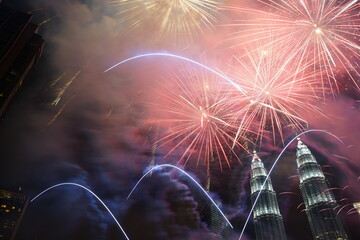 Kuala Lumpur, Malaysia – January 1, 2020: Colourful Fireworks spark during New Year at the Kuala Lumpur City. The image contains certain grain or noise and soft focus.