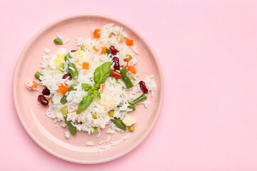Plate with tasty rice, beans and vegetables on color background