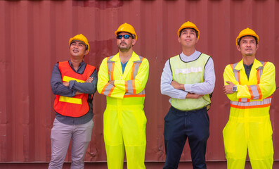 Group of professional dock worker and engineering people wearing hardhat safety helmet and safety vest standing and Looking at the machine, lifting the container trainer into the storage area.