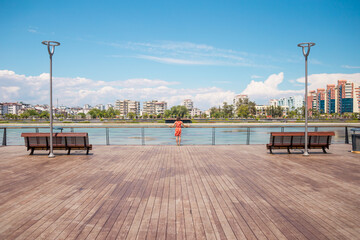 A girl in a dress walks on the promenade of Antalya