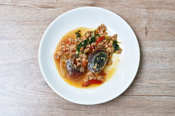 slice boiled  black preserved egg dressing spicy fried chop pork and basil leaf on plateleaf