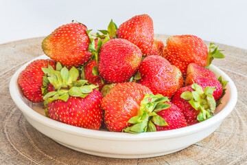 Strawberries in a plate on the table on a white background.