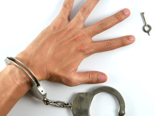 Handcuffs on the hands of the criminal on white background.