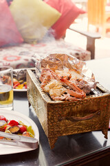 Seafood with crab, squid and shrimps on a cooper grill with drink and vegetables in cafe .