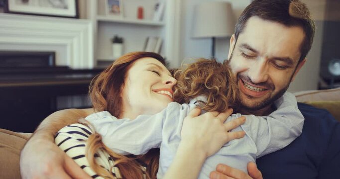 Сute little boy hugs mom and dad. Lovely young parents hugging with their youngest son. Happy family enjoying sweet life moment.