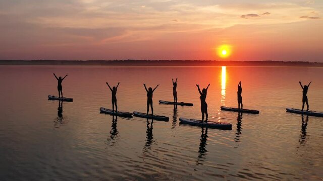 A group of girls doing yoga on the sup boards