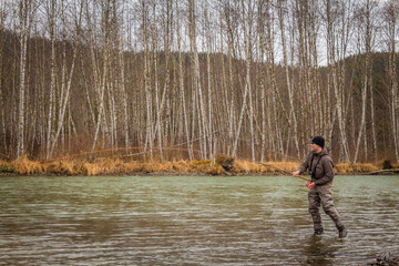 A fly fisherman hooked into a big fish with the rod bent, on the Kalum River, Skeena Region, British Columbia, Canada
