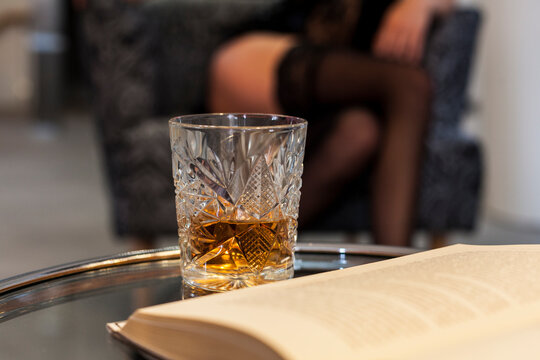 point of view of book reading person with glass of rum or whisky looking at woman in lingerie