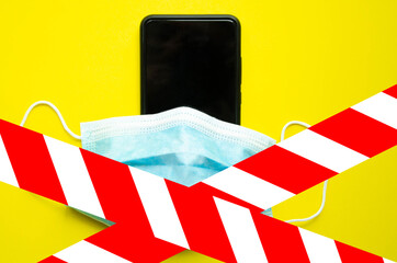 Blue medical mask on a black smartphone. Protection, disinfection of the smartphone. The mask is...
