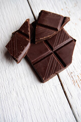 Dark chocolate bar top view mock up with space for text close up. Broken pieces of dark chocolate macro, mock-up for design. Food background over white wooden table.